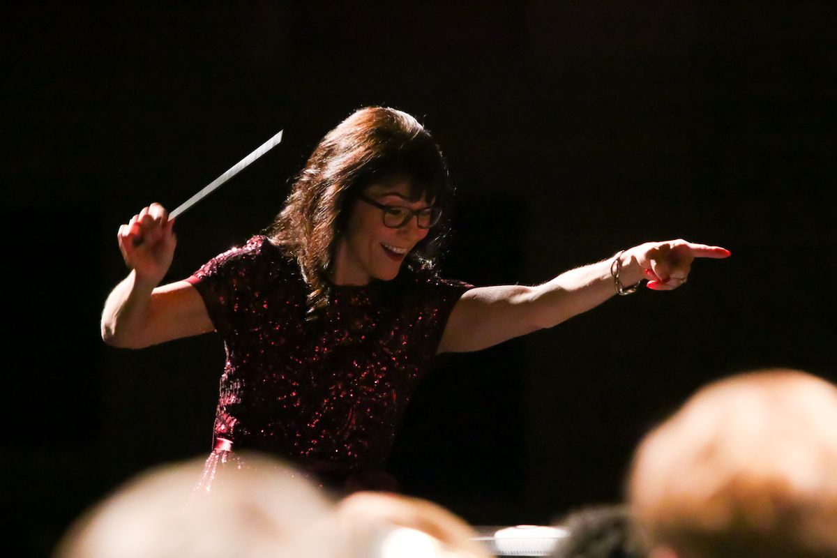 Andrea Strauss, baton raised and pointing mid-performance at the District 12 Honor Band concert